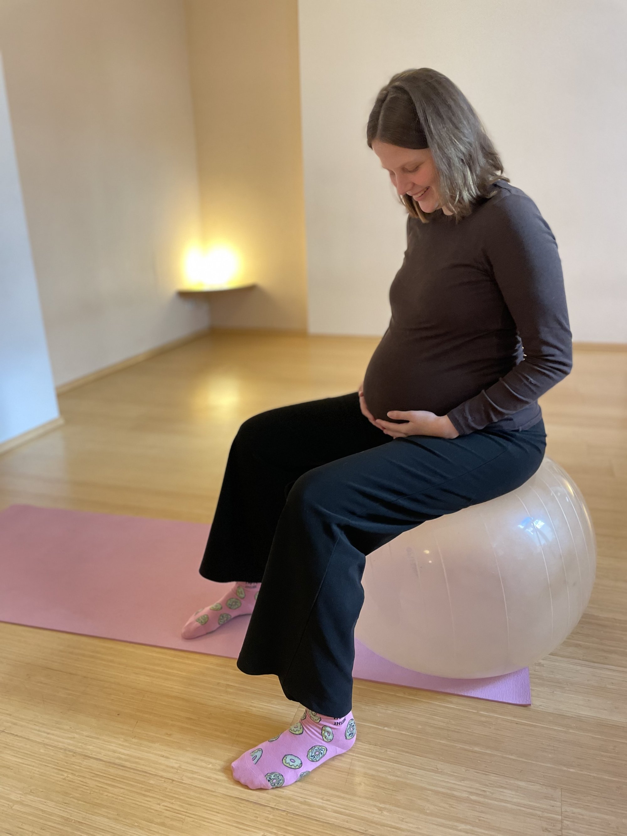 Schwangere auf dem Gymnastikball im ruhigen Kursraum