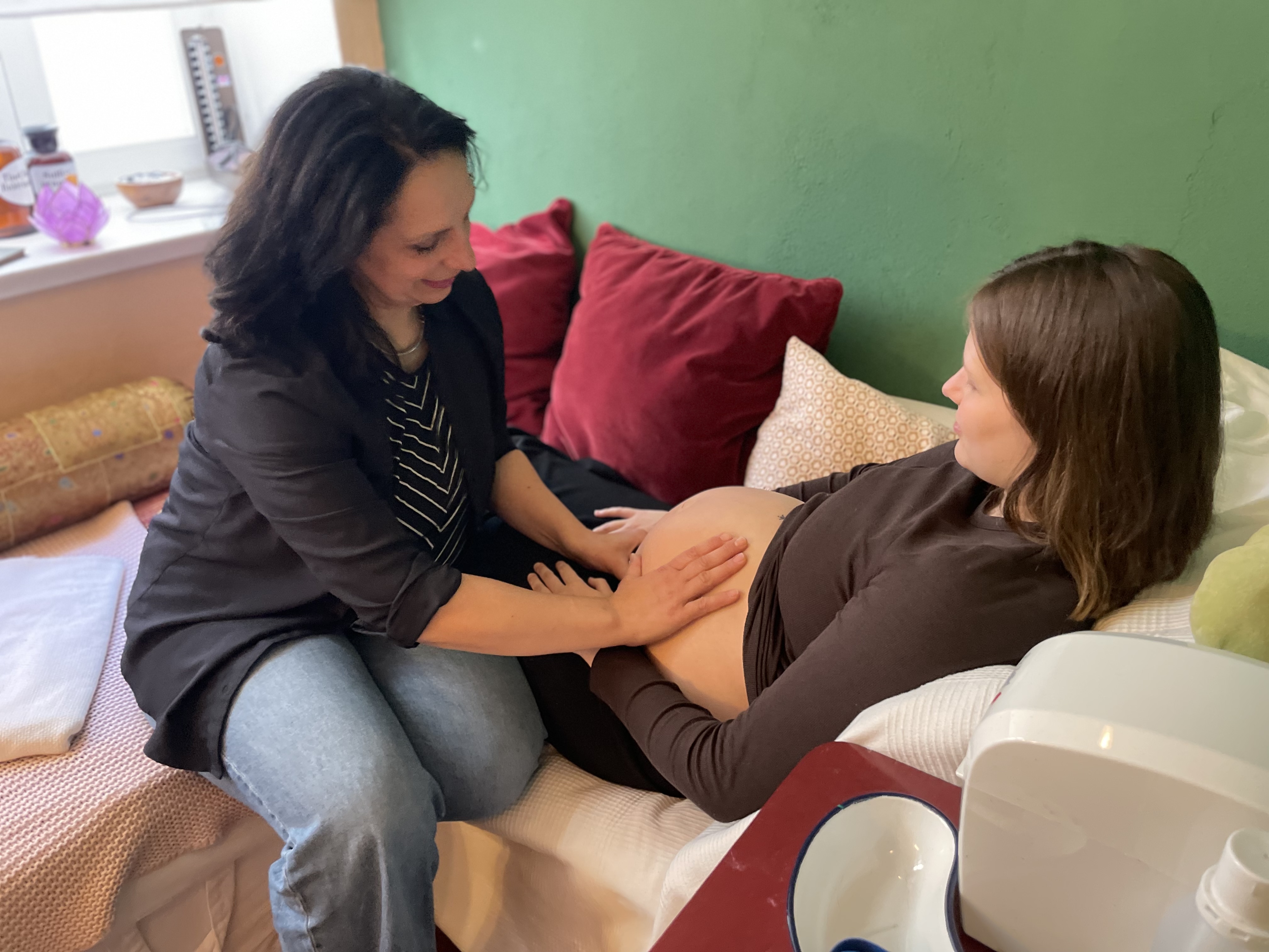 Claudia tastet den Bauch einer schwangeren Frau